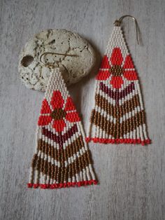 a pair of beaded earrings sitting on top of a table next to a rock