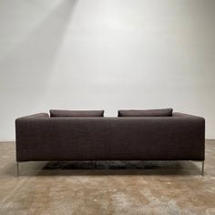 a brown couch sitting on top of a carpet covered floor next to a white wall