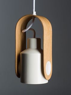 a white and wooden light hanging from a hook on a gray wall next to a bottle