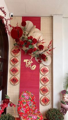 there is a red chair in front of a wall with flowers and decorations on it