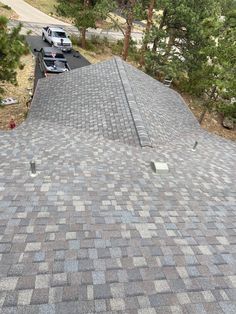 the roof of a house with two cars parked on it's sides and trees in the background