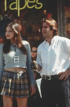 a man and woman standing next to each other in front of a store sign that says tapes