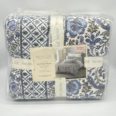 the blue and white bedspread is wrapped in plastic