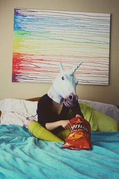 a person laying in bed with a horse head on top of their head and a bag of chips