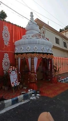 a decorated gazebo in the middle of a street next to a red fence and building