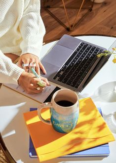 a person sitting at a table with a laptop and coffee cup in front of them