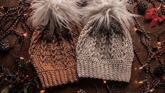 two knitted hats sitting next to each other on top of a wooden table with christmas decorations