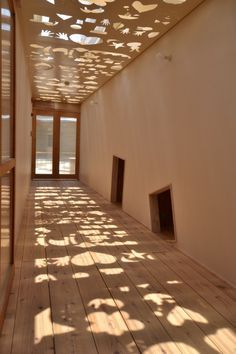 an empty room with wooden floors and shadows on the walls, windows in the ceiling