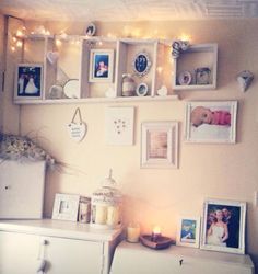 there are many pictures on the wall with lights around them and candles in front of them