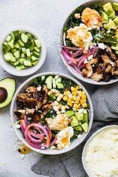 three bowls filled with different types of salads next to an avocado and cucumber