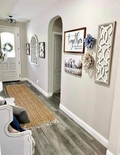 a living room filled with white furniture and pictures on the wall above it's doorway