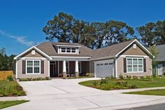 a house with two garages in front of it and trees on the other side