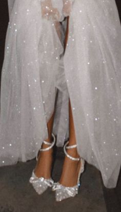 the bride is wearing her wedding dress and high heeled shoes with white sequins on them