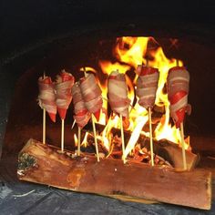 several skewered meats sitting on sticks in front of an open fire