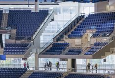 several people walking up and down the stairs in an empty auditorium with blue seats on either side