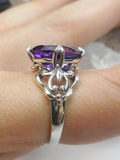 Natural Purple Amethyst RingSmall Fat Oval Design#D111 Inspired by Gothic designs, this stunning antique reproduction ring is crafted in sterling silver. This gorgeous ring is set with a flawless oval-cut natural purple amethyst. The stunning 3 carat weight gemstone is 11mm x 9mm. The band is marked 925 for sterling silver. Notice the beautiful silver filigree swirl setting and band. The bold style travels around the base of the gem and morphs into a solid band. The stunning gem rises above the Elegant Oval Purple Rings, Exquisite Oval Amethyst Ring For Wedding, Exquisite Oval Amethyst Wedding Ring, Exquisite Oval Amethyst Ring For Anniversary, Elegant Amethyst Marquise Ring, Heirloom Style Oval Amethyst Sterling Silver Ring, Exquisite Oval Purple Ring, Exquisite Oval Amethyst Ring With Center Stone, Heirloom Style Oval Amethyst Ring In Sterling Silver