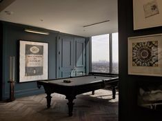 a pool table is in the middle of a room with large windows and pictures on the wall