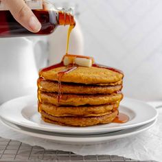 a stack of pancakes with syrup being poured on top