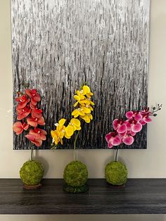 three vases filled with flowers sitting on top of a shelf next to a painting