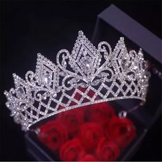 a tiara with roses in the foreground and a box of red roses in the background