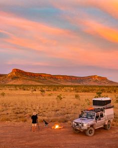 two people standing around a campfire in the desert