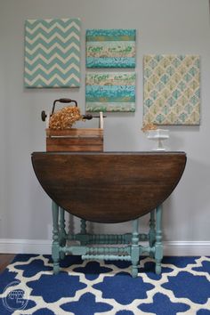 a blue rug in front of a wooden table with pictures on the wall behind it