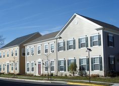 two story apartment building with white trim and green shutters on the front, along an empty street