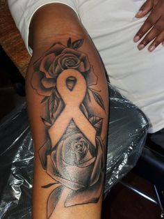 a woman's arm with a rose tattoo on it and a ribbon in the middle