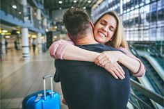 a man and woman hugging each other in an airport