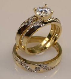 two gold wedding rings with diamonds on top and one diamond in the middle, against a white background