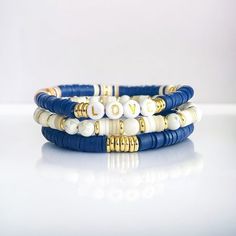 "Stunning Beaded Stack of Stretch Bracelets you can personalize, handcrafted with delicate blue, white, and gold beads that will add a touch of elegance to any outfit. This fashion accessory includes a stack of three bracelets that are adjustable, providing a unique and comfortable style. Our bracelets have been designed with high-quality materials, expertly crafted to ensure durability and long-lasting wear. The stretchable feature makes them a versatile option collection that can easily wrap a Blue Stackable Beaded Bracelets As Gift, Blue Stackable Heishi Beads Bracelets, Blue Heishi Beads Bracelets As Gift, Customizable Blue Friendship Bracelets As Gift, Customizable Blue Friendship Bracelets For Gifts, Adjustable Blue Bracelets For Birthday, Blue Stackable Round Bead Friendship Bracelets, Blue Round Bead Bracelet For Birthday, Blue Beaded Friendship Bracelets For Birthday