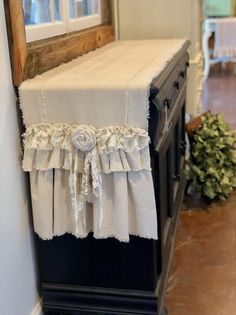 a black dresser with a white table cloth on it