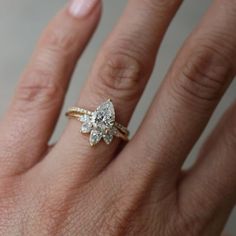 a woman's hand with a diamond ring on top of her finger and an engagement band