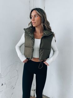 DETAILS: Our Colt Puffer Vest is an olive puffer vest with a cropped fit. This vest features a cropped fit and cinchable detail on the hemline to create a more customizable fit. This puffer vest is completed with a black monochromatic zipper closure. CONTENT & CARE: SELF: 100% Polyester SIZE & FIT: Model is 5'6" The model is wearing a size Small. Fits true to size The Fabric has stretch Green Puff Vest Outfit, Puff Vest Outfit, Vest Outfits For Women, Puff Vest, Cropped Vest, Custom Jacket, Vest Outfits