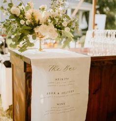 a table that has some wine glasses on it and flowers in vases next to it