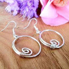 A pair of simple spiral dangle drop hoop earrings, made with thick silver wire. Wire wrapped jewellery that makes a great unique Mothers day gift with a bohemian style or a funky pair of festival earrings. These earrings have been hand shaped in thick 1.5mm silver wire into hoops with simple spirals, they have then been hammered slightly flat.  They can be made in either silver plated (nickel and lead free with an anti tarnish finish) or 925 sterling silver. Use the variations box to choose. 💝 Wire Wrapped Jewellery, Silver Wire Jewelry, Celtic Spiral, Bijoux Fil Aluminium, Festival Earrings, Unique Mothers Day Gifts, Jewellery Gifts, Spiral Earrings, Hand Shapes