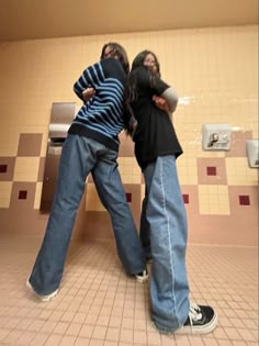 two people standing in a public restroom with their arms around each other's backs