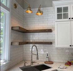 a kitchen with white cabinets and marble counter tops, two hanging lights above the sink