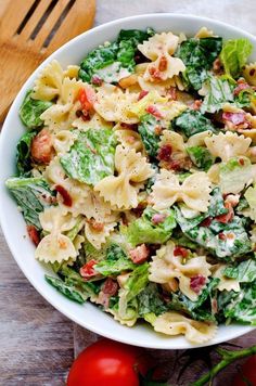 a white bowl filled with pasta salad on top of a wooden table