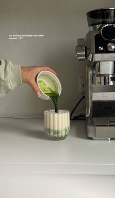 a person pouring green liquid into a cup