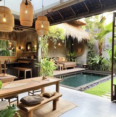 an outdoor dining area next to a pool with lights hanging from the ceiling and plants in pots