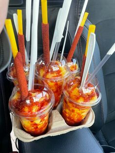 four plastic cups filled with food sitting on top of a seat in the back of a car