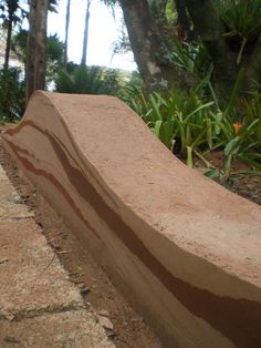 a stone bench sitting in the middle of a park next to some trees and plants