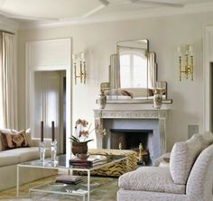 a living room filled with furniture and a fire place in front of a mirror on the wall