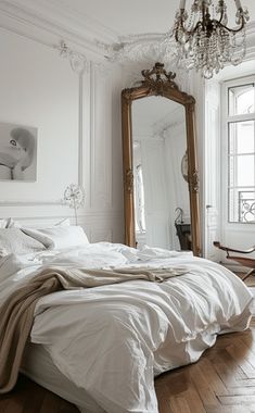 a bedroom with a bed, mirror and chandelier on the wall next to it