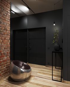 a large metal bowl sitting on top of a wooden floor next to a brick wall