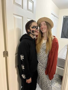 two people with face paint standing next to each other in front of a white door