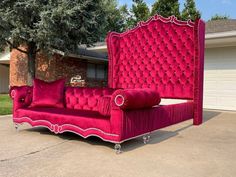 a pink couch sitting on top of a sidewalk next to a tree and garage door