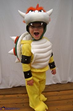 a little boy dressed in a costume that looks like a dragon with horns and tail