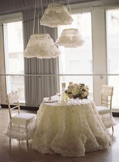 the table is set with white linens and chandeliers hanging from the ceiling